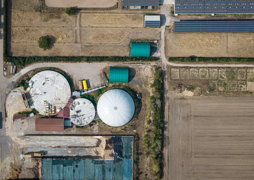 Aerial view of a biogas plant’s circular tanks among farmland