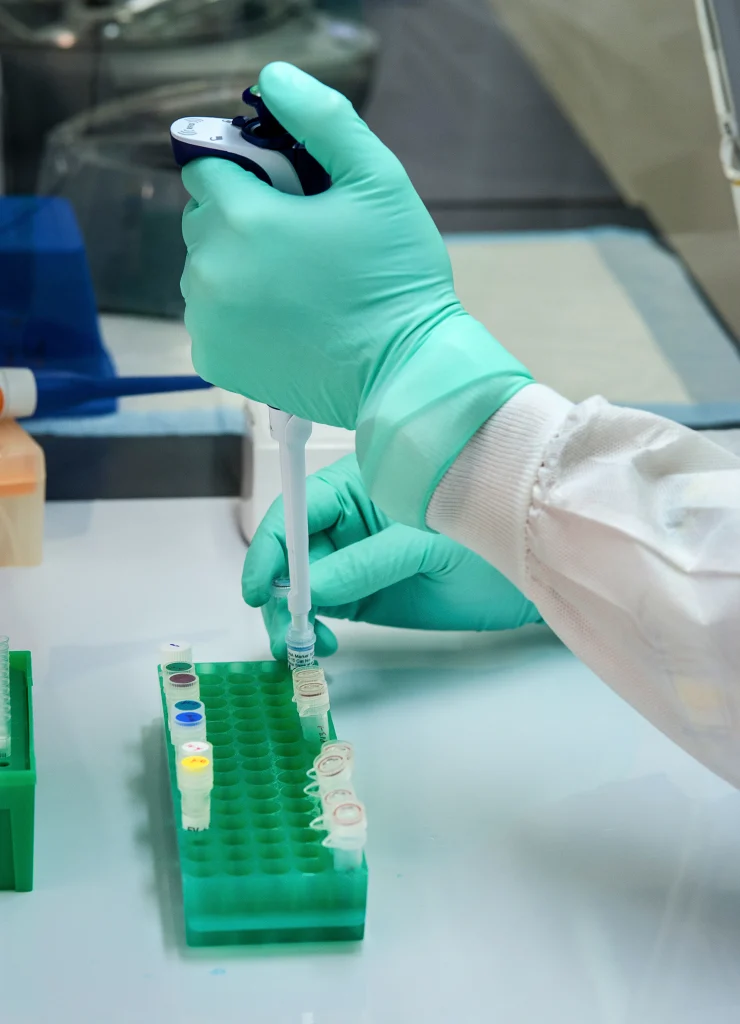 Gloved hand pipetting a sample into a vial